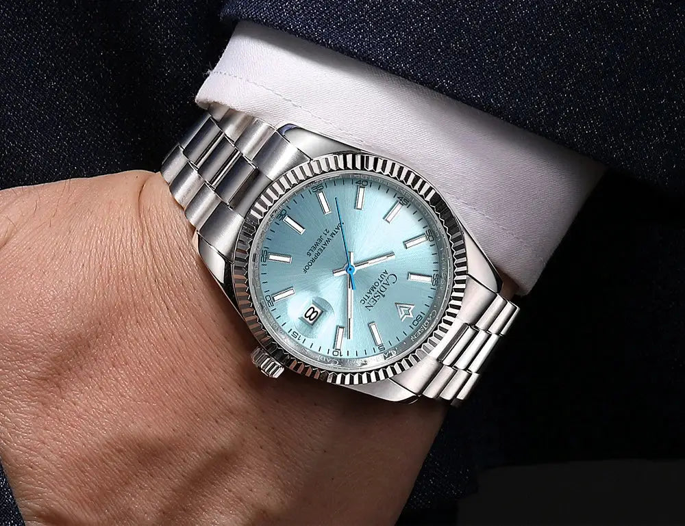 CADISEN men's stainless steel automatic watch with light blue dial, fluted bezel, and date window.