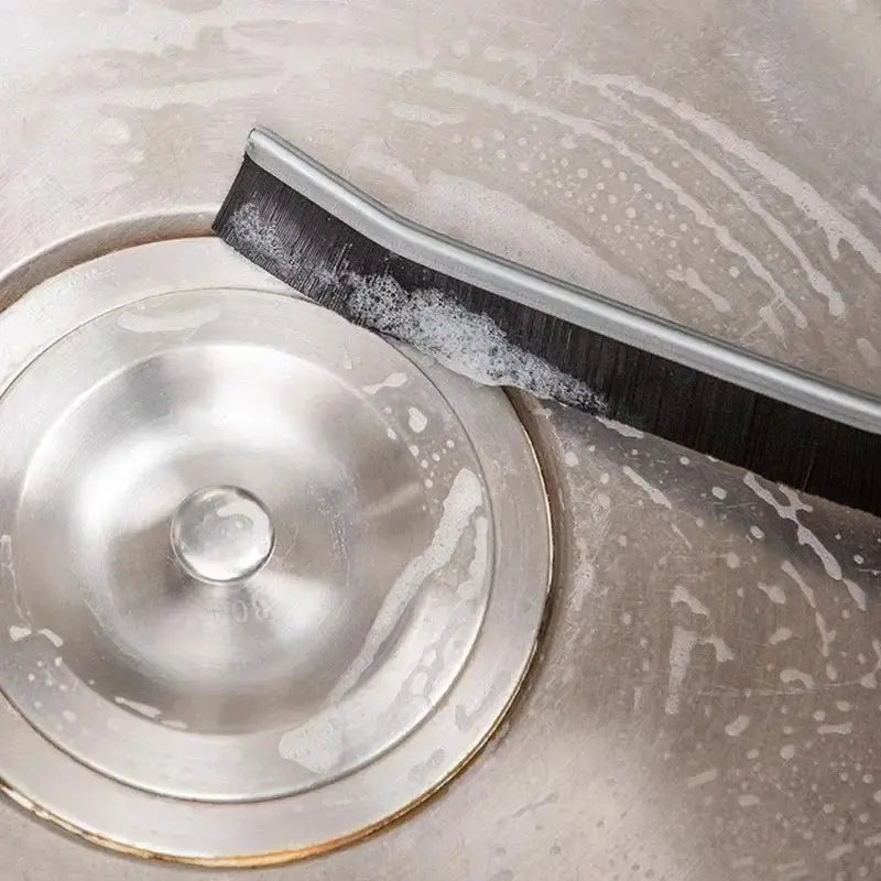 Grout cleaning brush by Simples Market with curved head and hard black bristles for tile joints and shower floor.