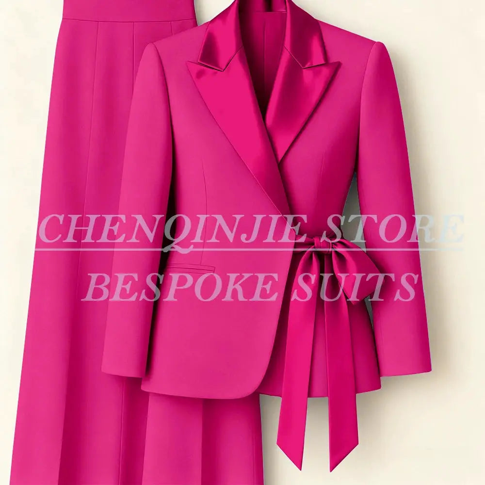 Pink women's two-piece blazer and pants suit with peak lapel and waist-tie belt.