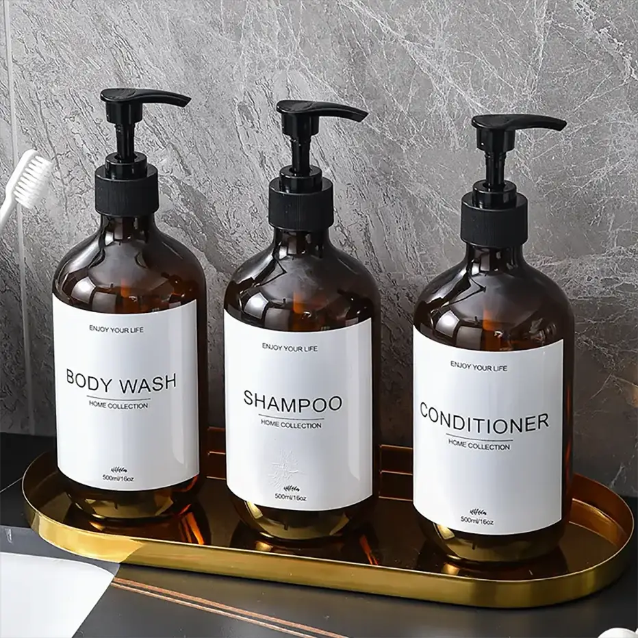 3-pack amber glass pump-dispenser bottles: body wash, shampoo, conditioner on a gold tray