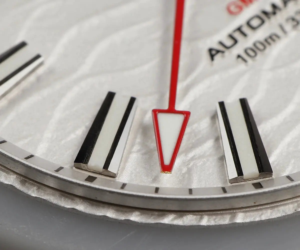 Cronos GS mechanical men's watch dial close-up with red GMT arrow, white dial, and black baton hour markers.