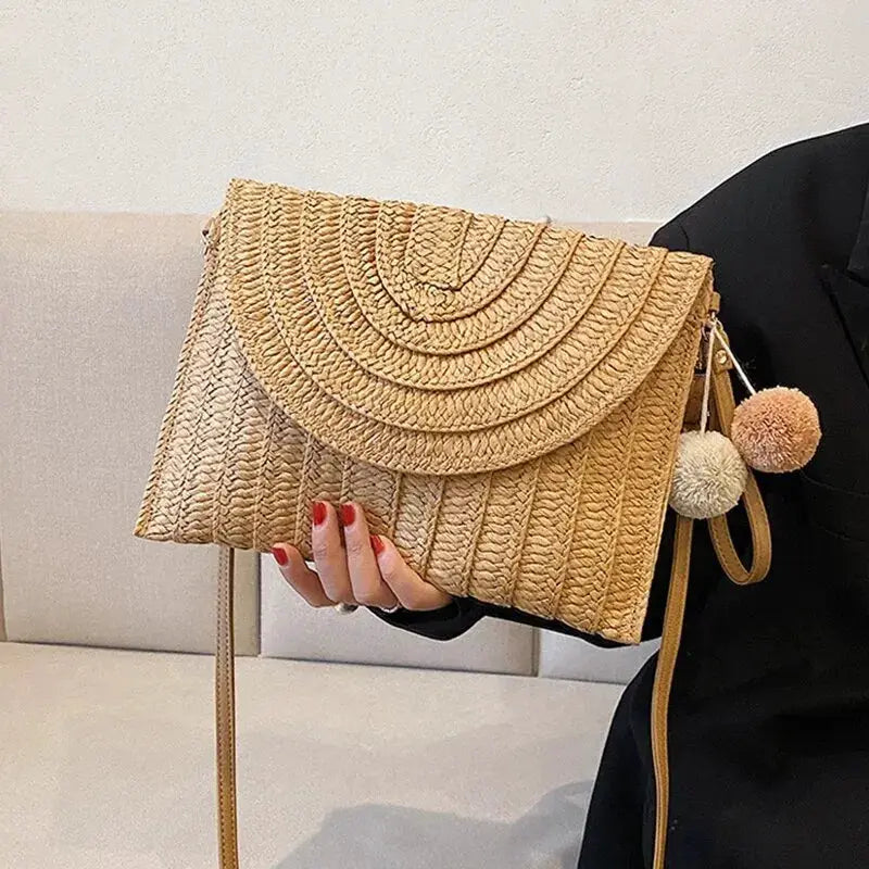 Handmade straw beach shoulder crossbody bag with envelope flap, woven natural color, pom-pom charm.