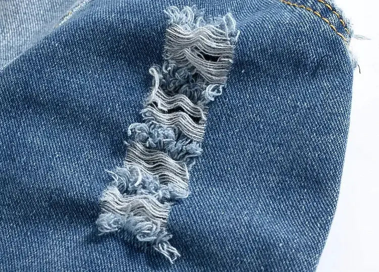 Denim jeans fabric close-up in blue with distressed frayed ripped seam