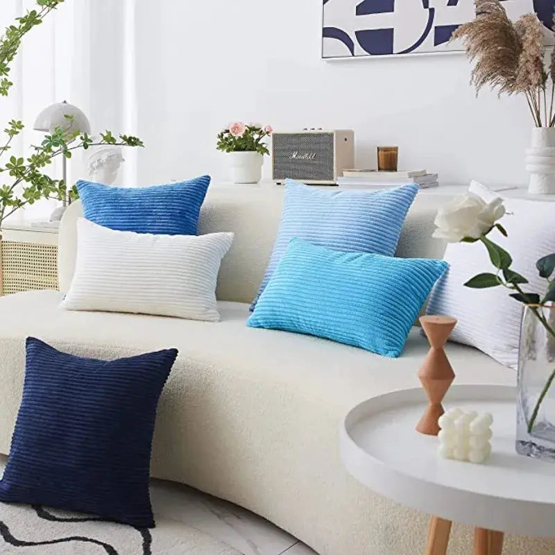 Corduroy striped pillow covers set in blue tones and white on a cream sofa