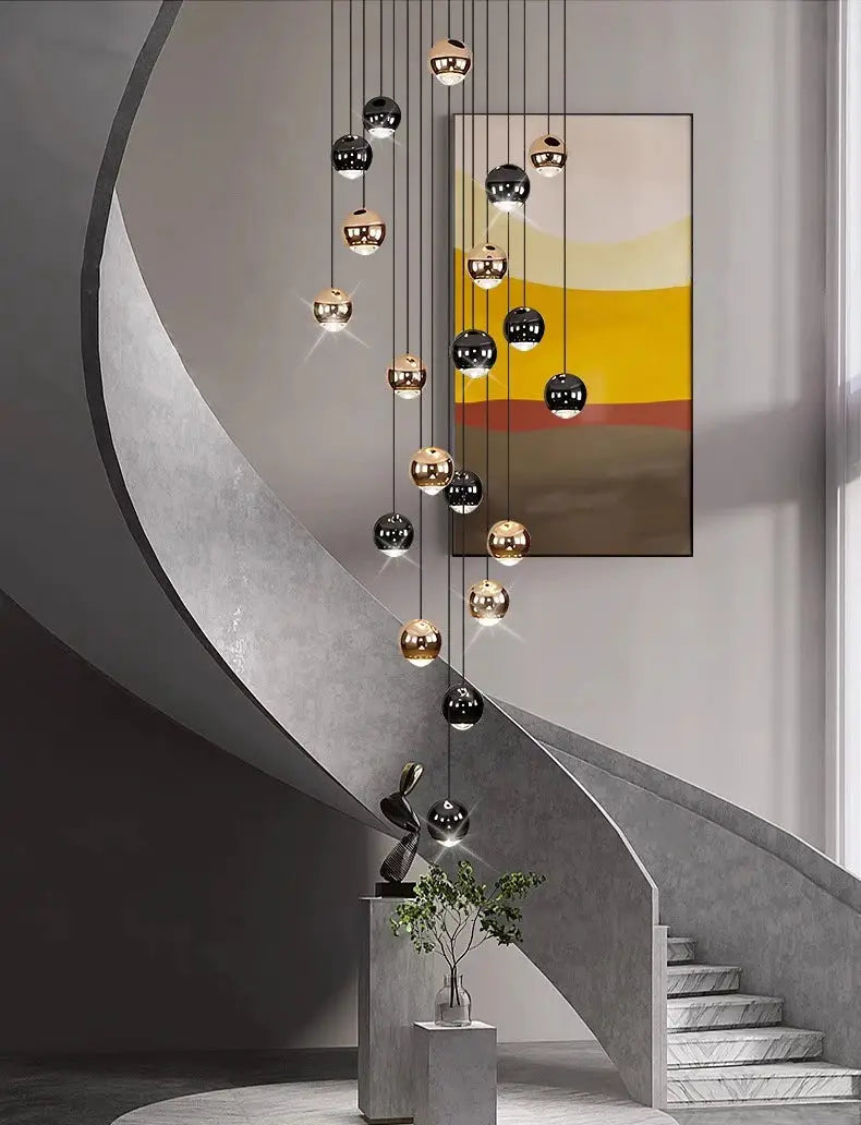 Modern pendant light with metallic gold and black spherical LED bulbs, clustered over a curved staircase.