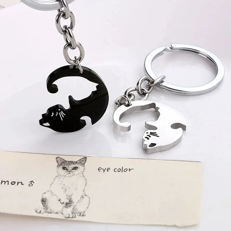 Cat hug keychain set featuring a black round cat silhouette charm and a silver cat-cutout charm on a metal keyring