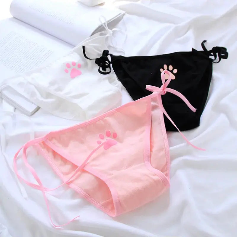 Women’s cotton panties set in pink, white, and black with pink paw-print motif and side lace-up straps