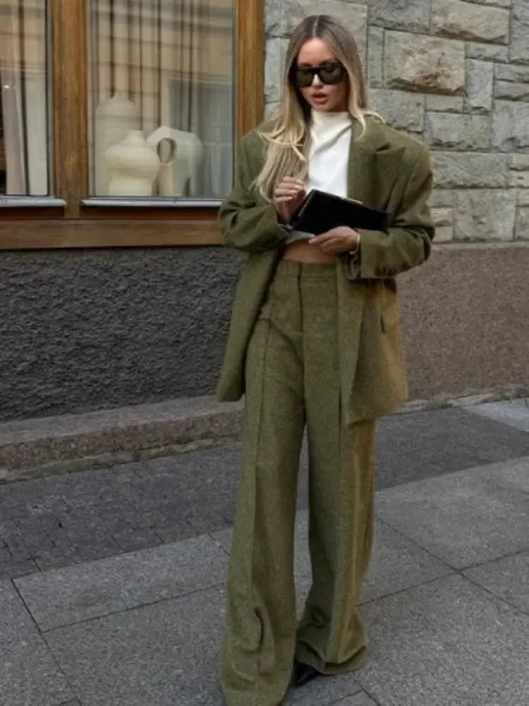 Olive green blazer and matching wide-leg pants two-piece set worn with a white top and sunglasses.