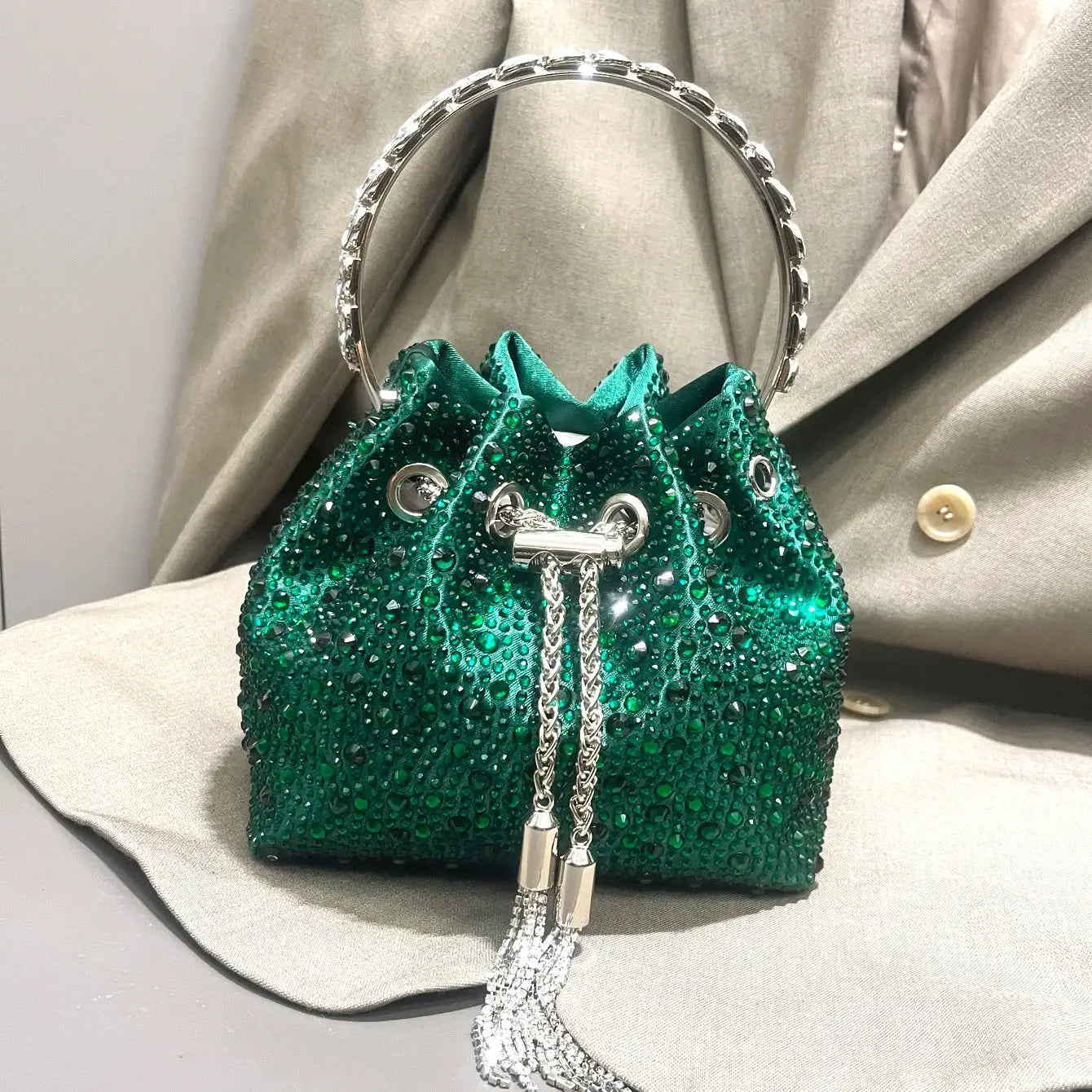 Emerald-green rhinestone clutch bag with silver hoop handle and chain tassels