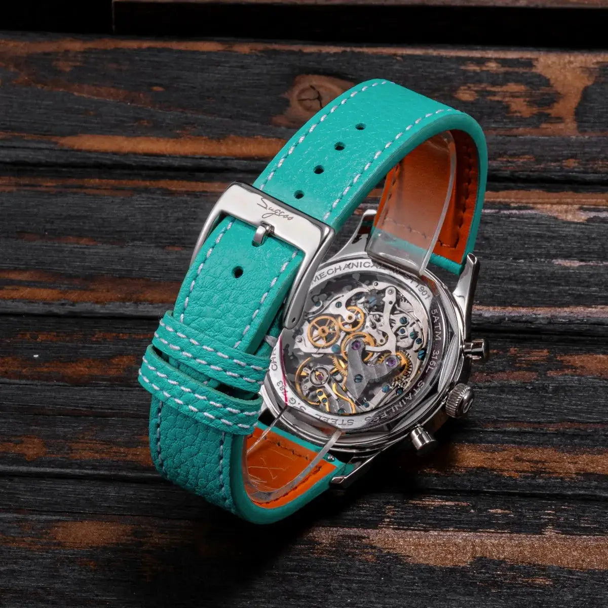 Sugess chronograph watch with turquoise leather strap (orange lining) and visible skeleton movement.