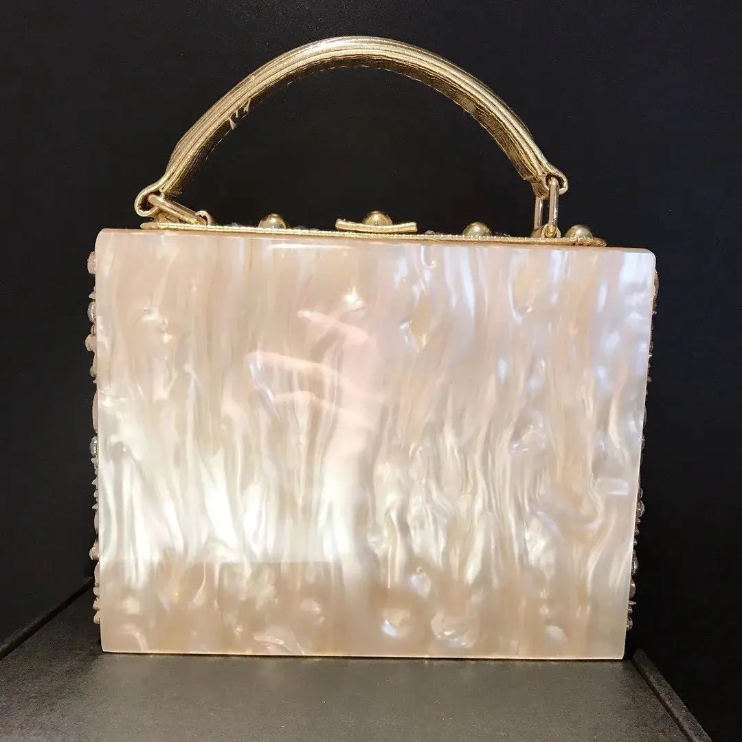 Pearl-mother-of-pearl evening bag with crystal-embellished edges and gold handle