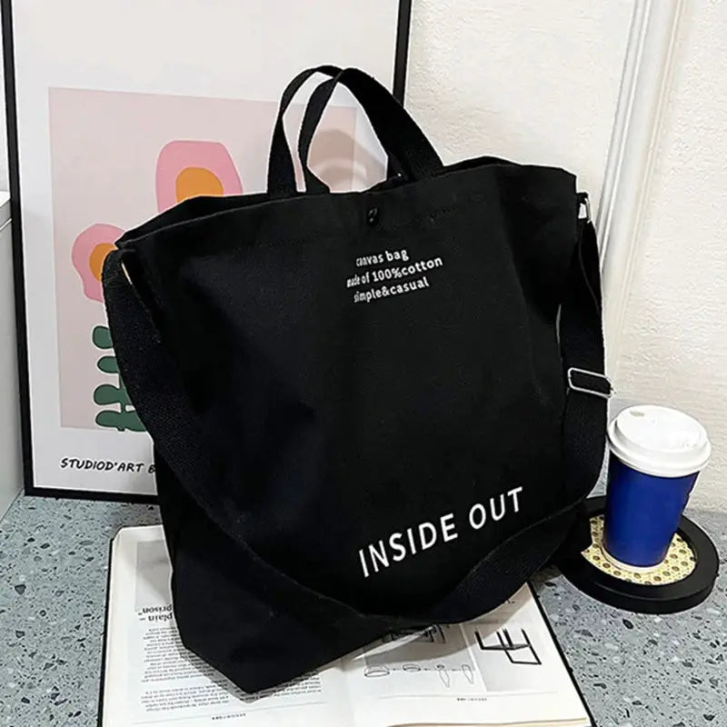 Black canvas cross-body bag with adjustable strap, large capacity and INSIDE OUT text