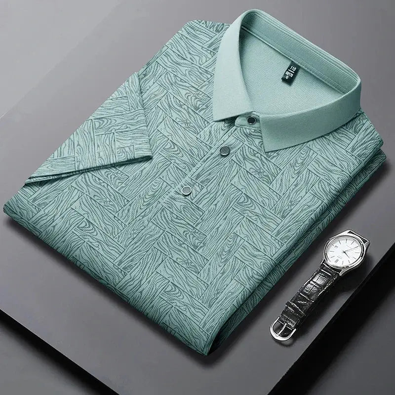 Men's polo shirt by Simples Market in teal geometric print with short sleeves; folded beside a black leather watch (two items)
