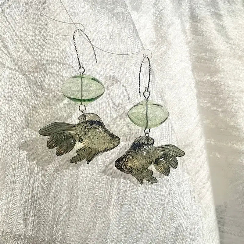 Pair of goldfish pendant earrings with transparent green fish charms and green beads on silver hooks