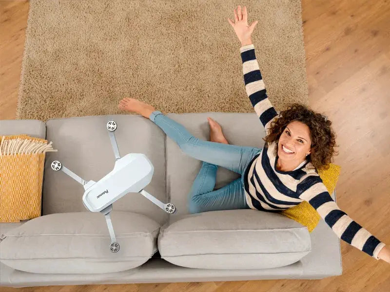 Potensic white quadcopter on a gray sofa beside a smiling woman