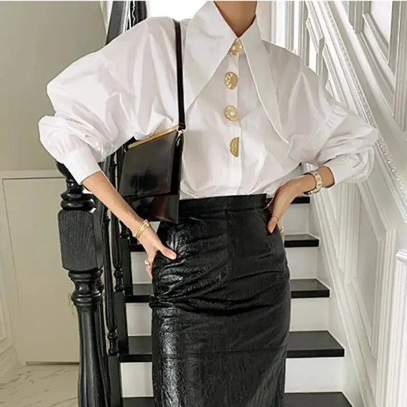 White pearl-button blouse with sharp collar and puff sleeves, paired with a black patent pencil skirt