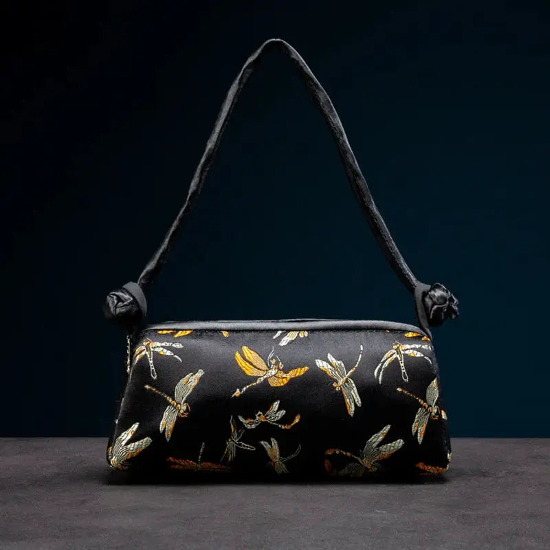 Small black satin shoulder bag with gold and silver dragonfly embroidery.