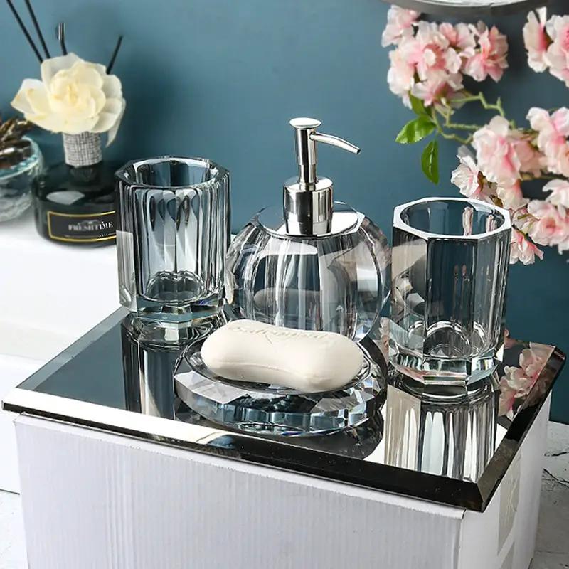 Crystal clear glass bathroom set on a mirrored tray with lotion pump, two tumblers, and soap dish with bar soap