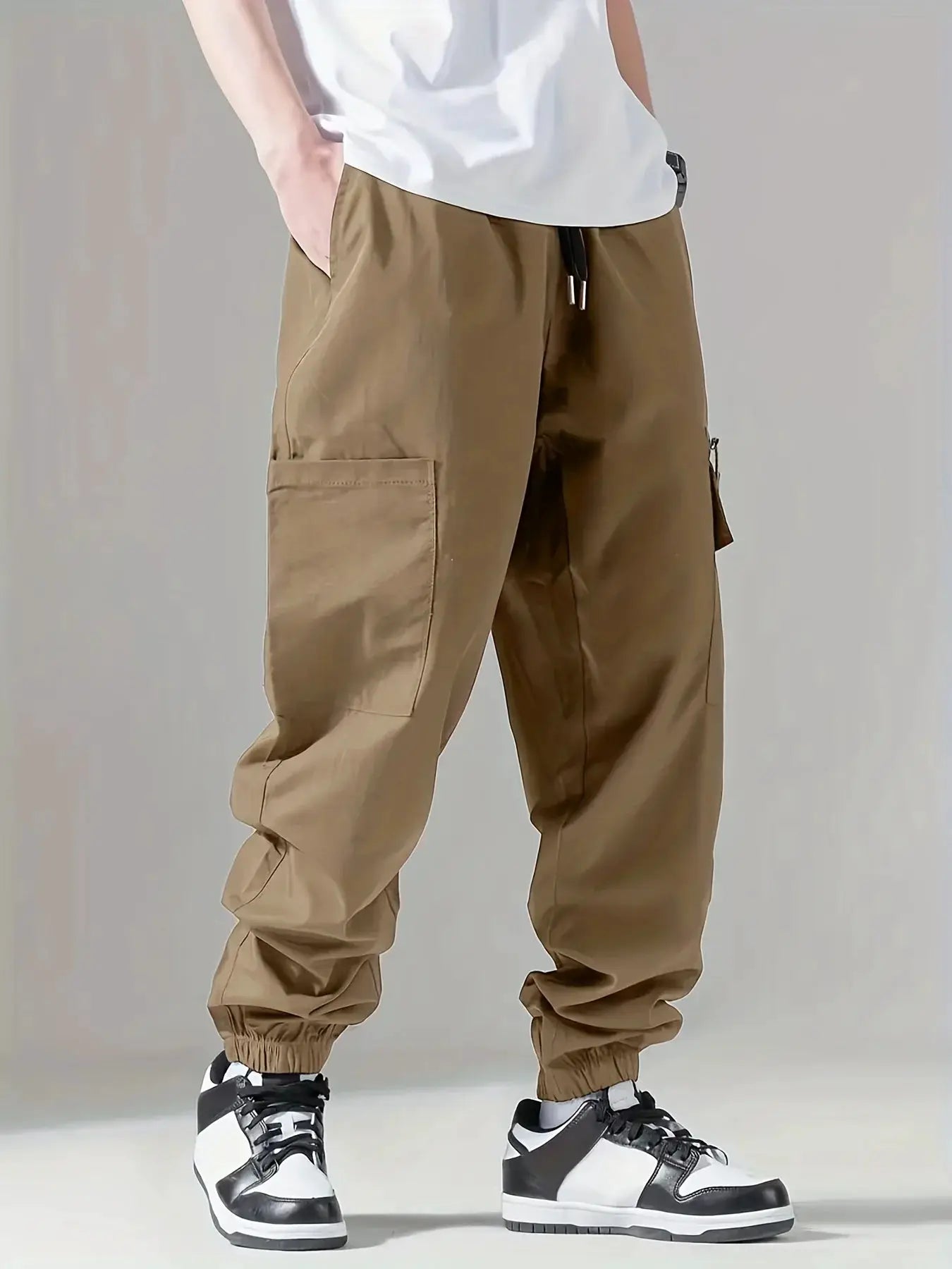 Men's cargo pants in tan with multi-pocket design, drawstring waist, and elastic cuffs.