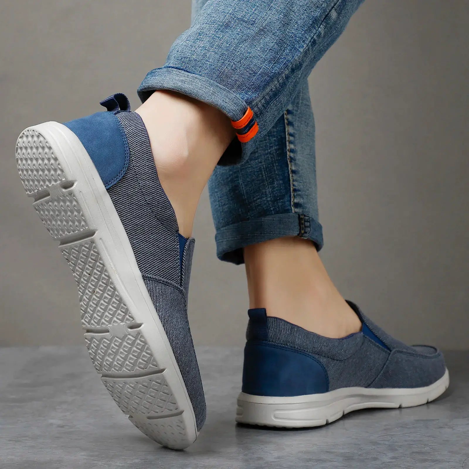 Men's blue denim canvas slip-on sneakers with white sole and orange pull tabs; breathable casual walking shoes