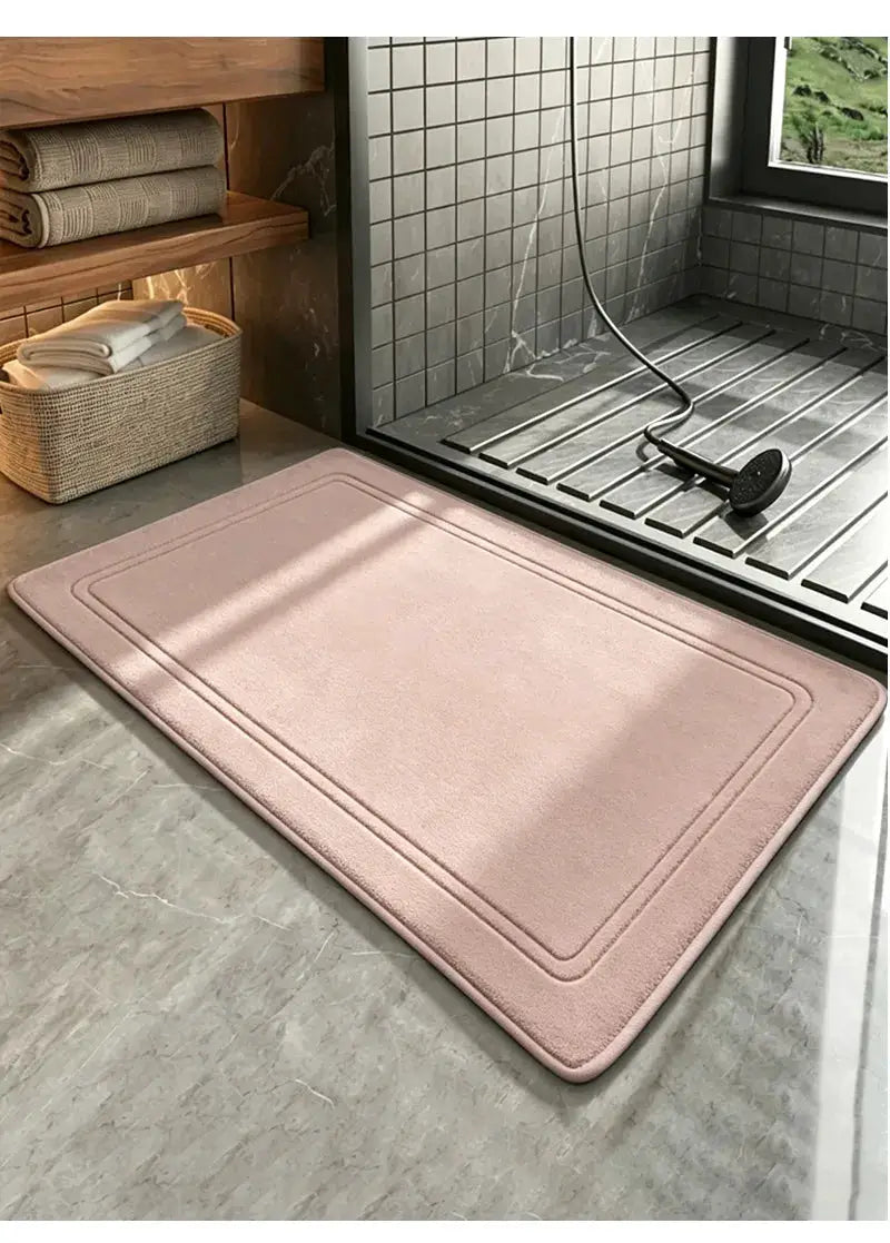 Pink bathroom rug mat placed in front of a walk-in shower with gray tiled walls and marble floor.