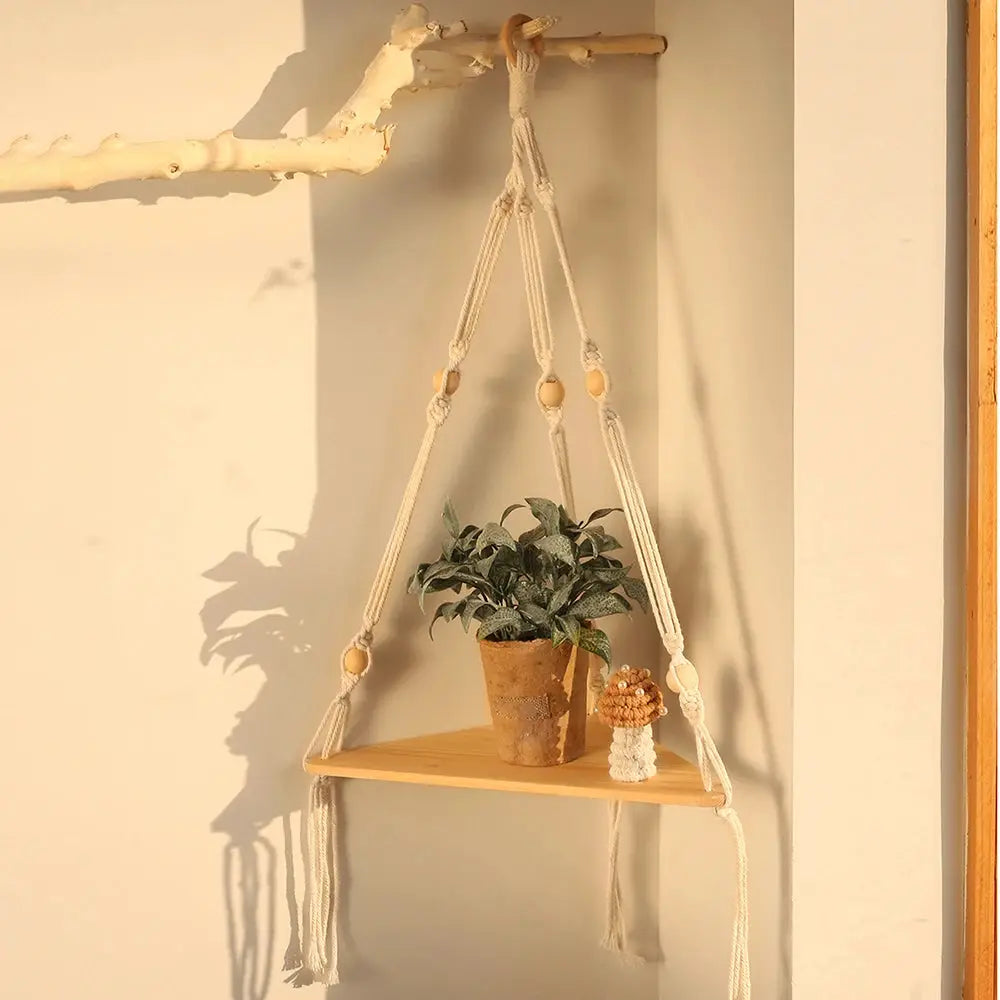 Floating wood triangle hanging shelf with macrame rope holding a potted plant and mushroom decor