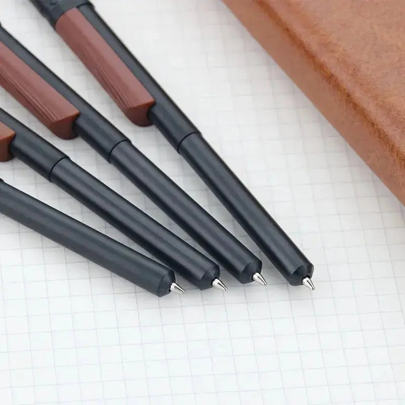 Gun-pen style ballpoint pen set of 4 with black bodies and brown grips on grid paper
