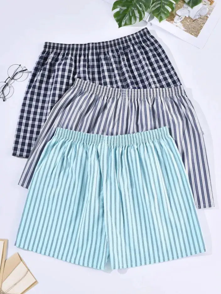 Three pairs of men's cotton sleep shorts in navy plaid, gray stripes, and light blue stripes with elastic waists