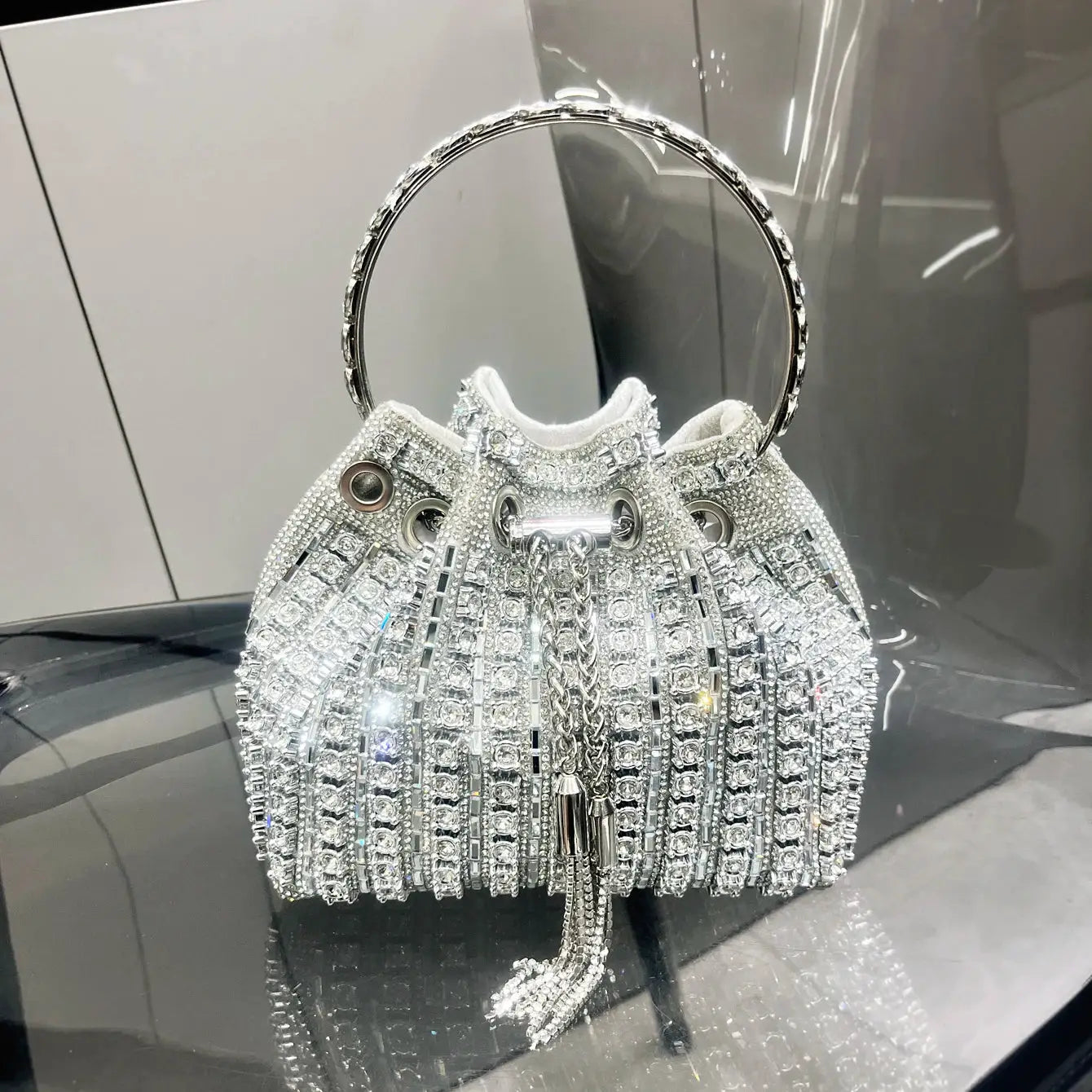 Silver crystal bucket clutch with round jeweled handle and tassel fringe for evening