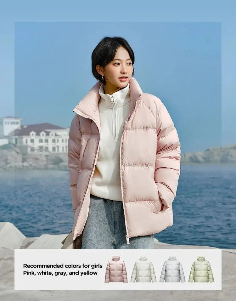 Pink short puffer down jacket worn by a woman at the seaside, featuring a high collar and quilted styling.