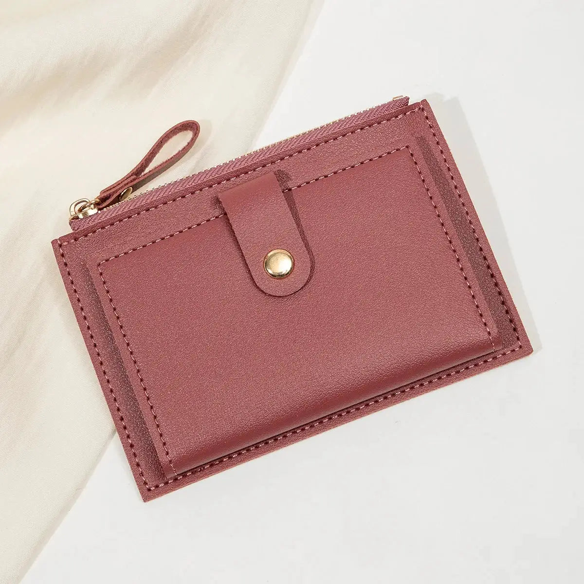 Minimalist women's short card wallet in pink PU leather with zip closure and snap strap