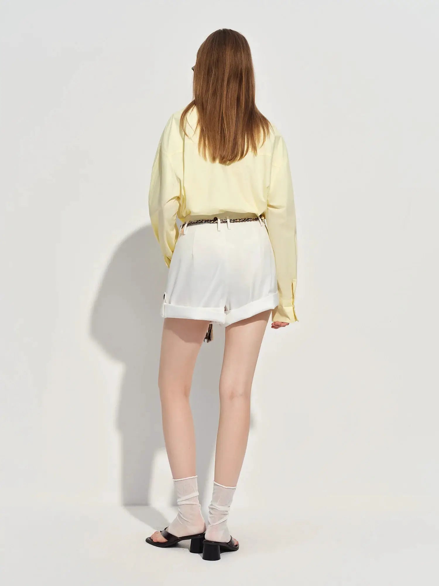 FSLE Premium Series women's loose-fit cotton shirt in pale yellow, back view with white rolled shorts and braided belt