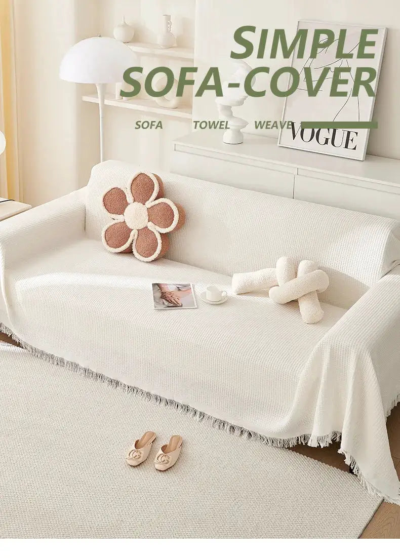 Cream wind-cotton yarn sofa cover with fringe trim, designed for universal all-season protection on a white sofa.