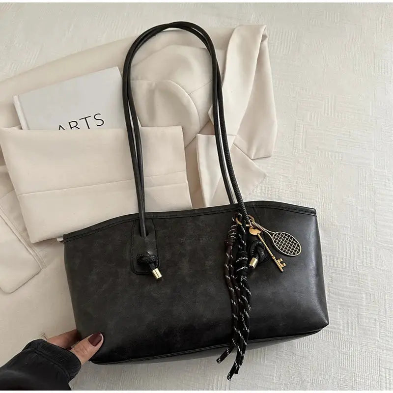 Black faux-leather European American retro tote bag with double handles, large capacity, and tassel charms.