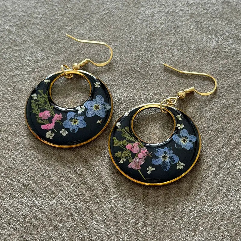 Pair of pressed flower earrings, black epoxy resin with pink and blue flowers, gold-tone hoops and hooks