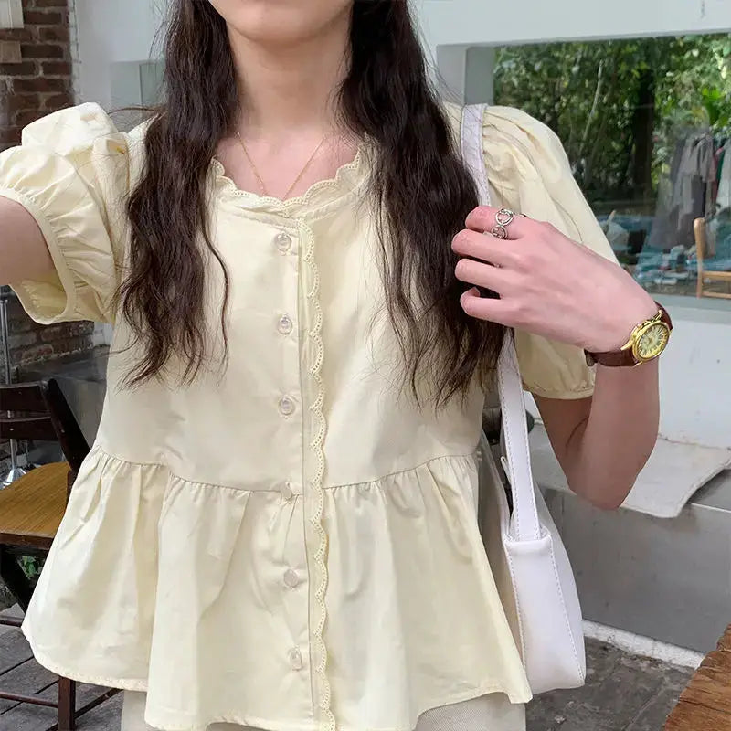 Women’s pale yellow puff-sleeve peplum blouse with scalloped lace trim and pearl buttons