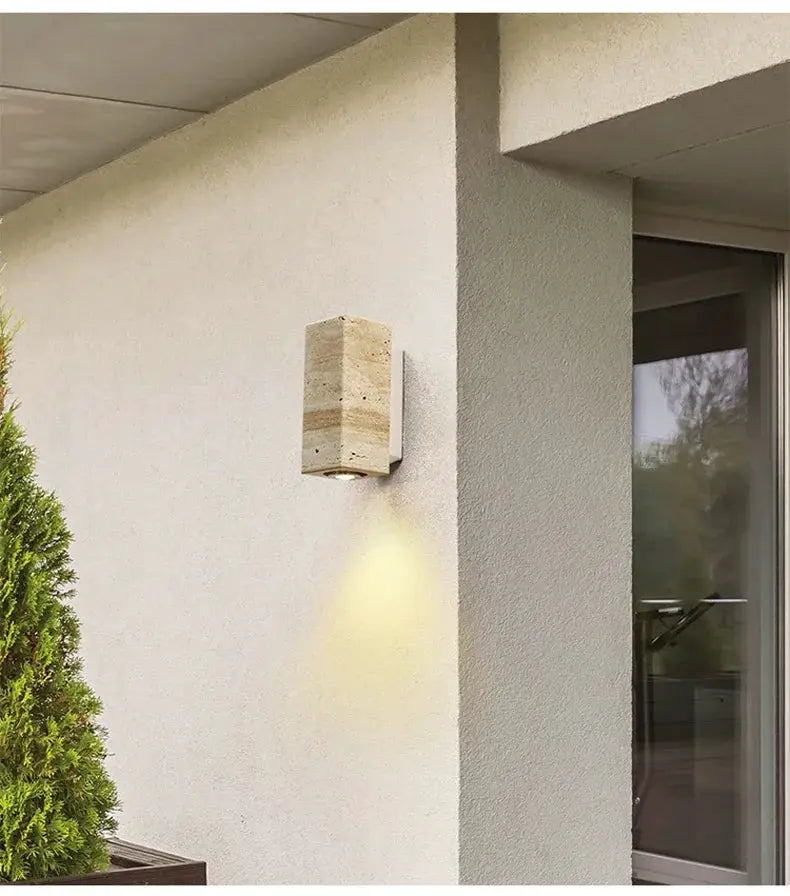 Wabi Sabi yellow marble wall lamp travertine sconce with warm downlight on an exterior stucco wall and outdoor decor