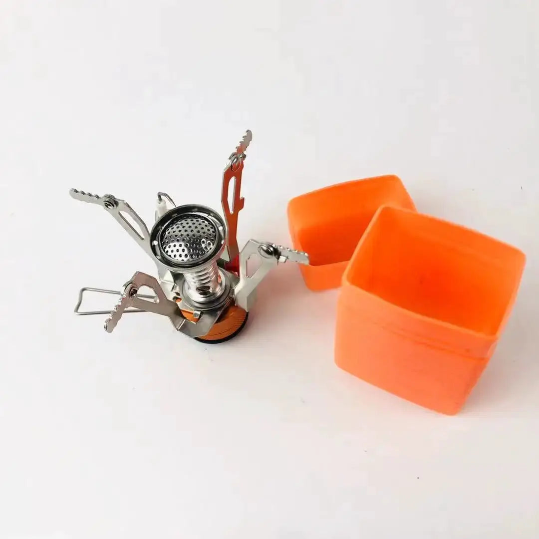 Portable aluminum camping stove with orange silicone cups and fold-out metal supports