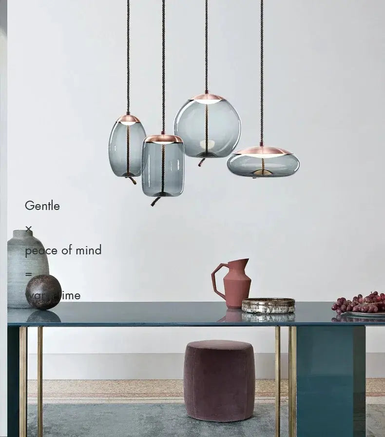 Minimalist pendant lamps by Simples Market; five blue glass pendants with copper caps on hemp rope cords.