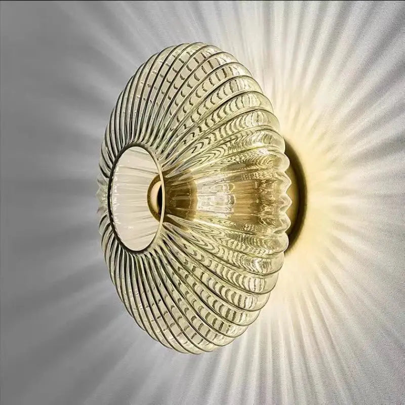 Nordic LED glass wall sconce with gold-toned circular ribbed design and warm glow