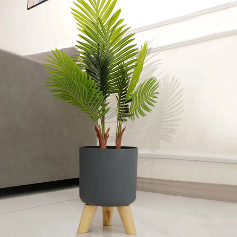 Simples Market floor-standing round plant pot with wooden legs, dark gray planter and leafy palm.
