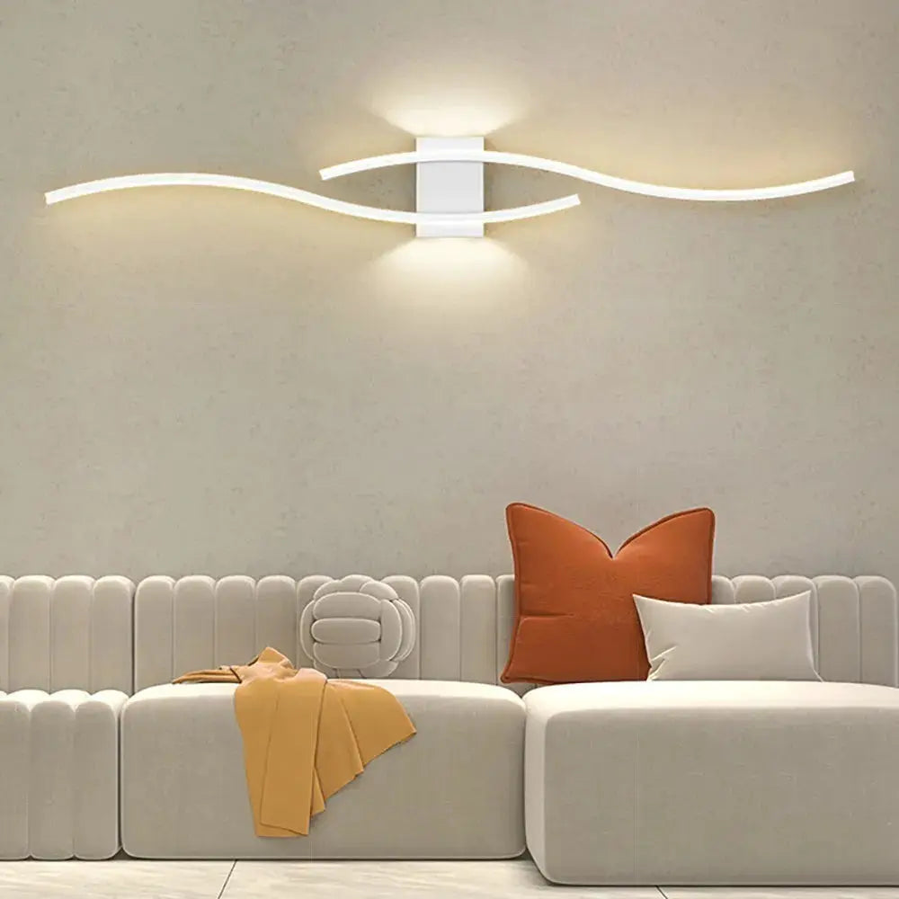 Moder LED wall lamp long strip with two white curved light bars and central mount, emits warm glow above sofa.