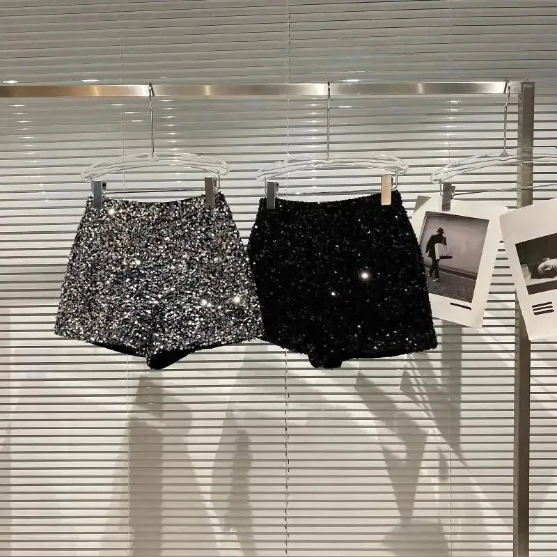 Two sequined velvet shorts on hangers, silver glitter and black, clubwear hot pants.