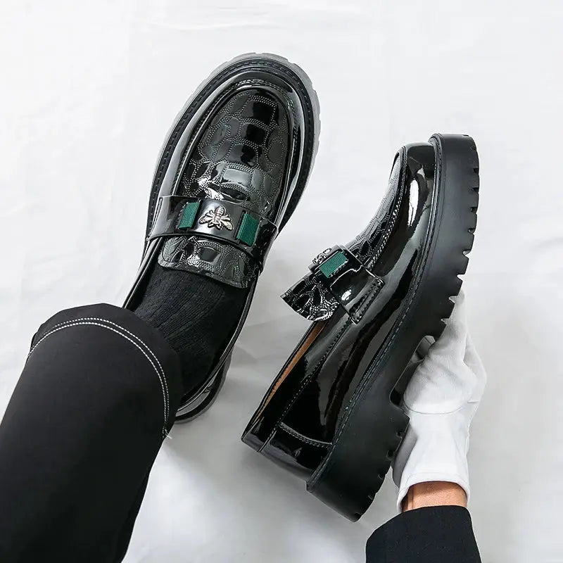 Pair of men's black patent leather slip-on loafers with thick lug soles and green strap accents.