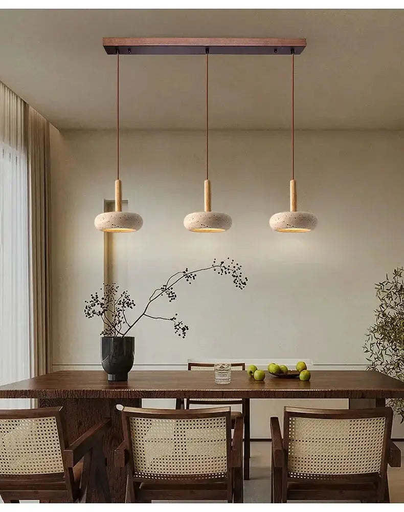 LED pendant lamp trio featuring circular yellow stone fixtures with warm light over dining table.