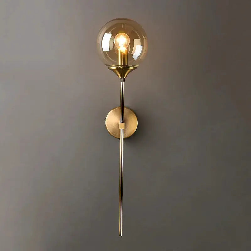 Modern glass wall lamp with a golden round globe and brass finish, Nordic style for bedside or living room.