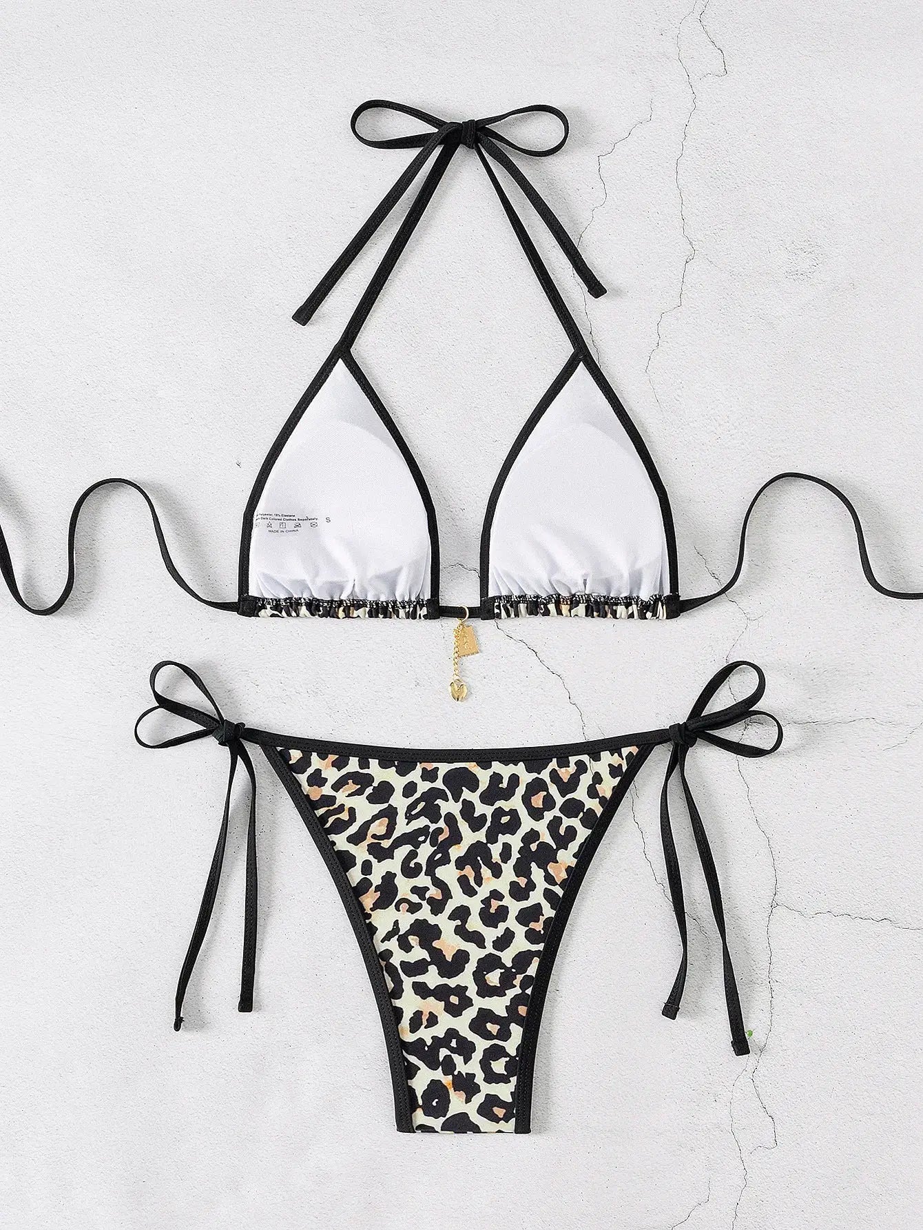 Two-piece triangle bikini set with white top, black trim, and leopard-print bottoms with side ties