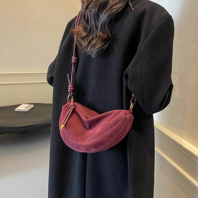 Simples Market faux suede crescent crossbody bag in burgundy with knotted strap worn by model