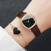 2-piece fashion watch set: gold-tone square-faced quartz watch with brown leather strap and black heart bracelet