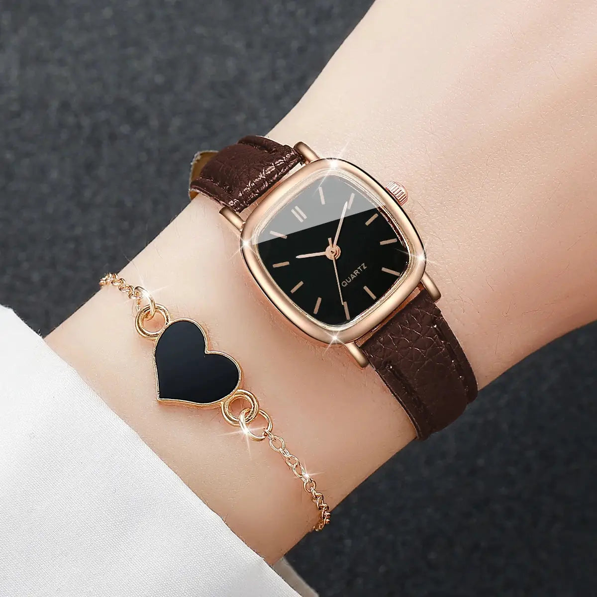 2-piece fashion watch set: gold-tone square-faced quartz watch with brown leather strap and black heart bracelet
